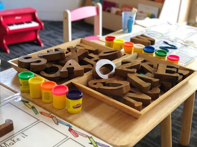 Alphabet letters and modelling dough on a child-sized table
